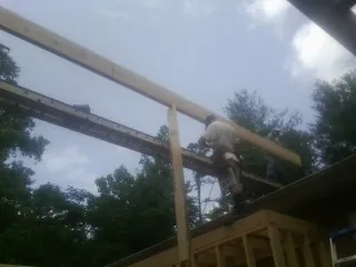 Carpenter setting a ridge beam over a new addition frame — Ice Dam Removal by Roofing Brothers in Fred