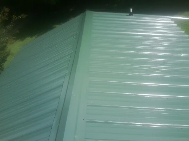 New green metal panels meeting at the ridge of a roof — Flat Roof Repair work by our crew in Fred