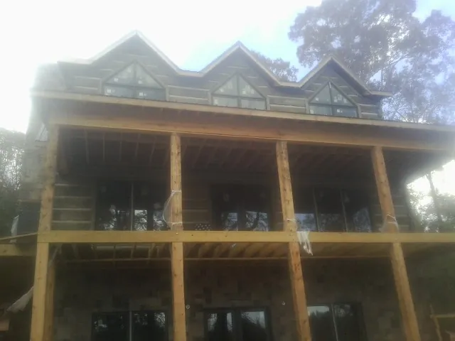 Dormers and porch framing on a large log home under construction — Roof Coating work by our crew in Fred