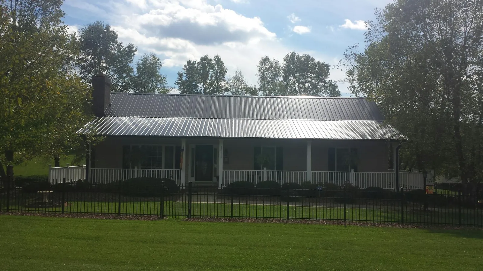 Gray metal roof on a brick ranch with a full width front porch — Gutter Guard Installation work by our crew in Fred