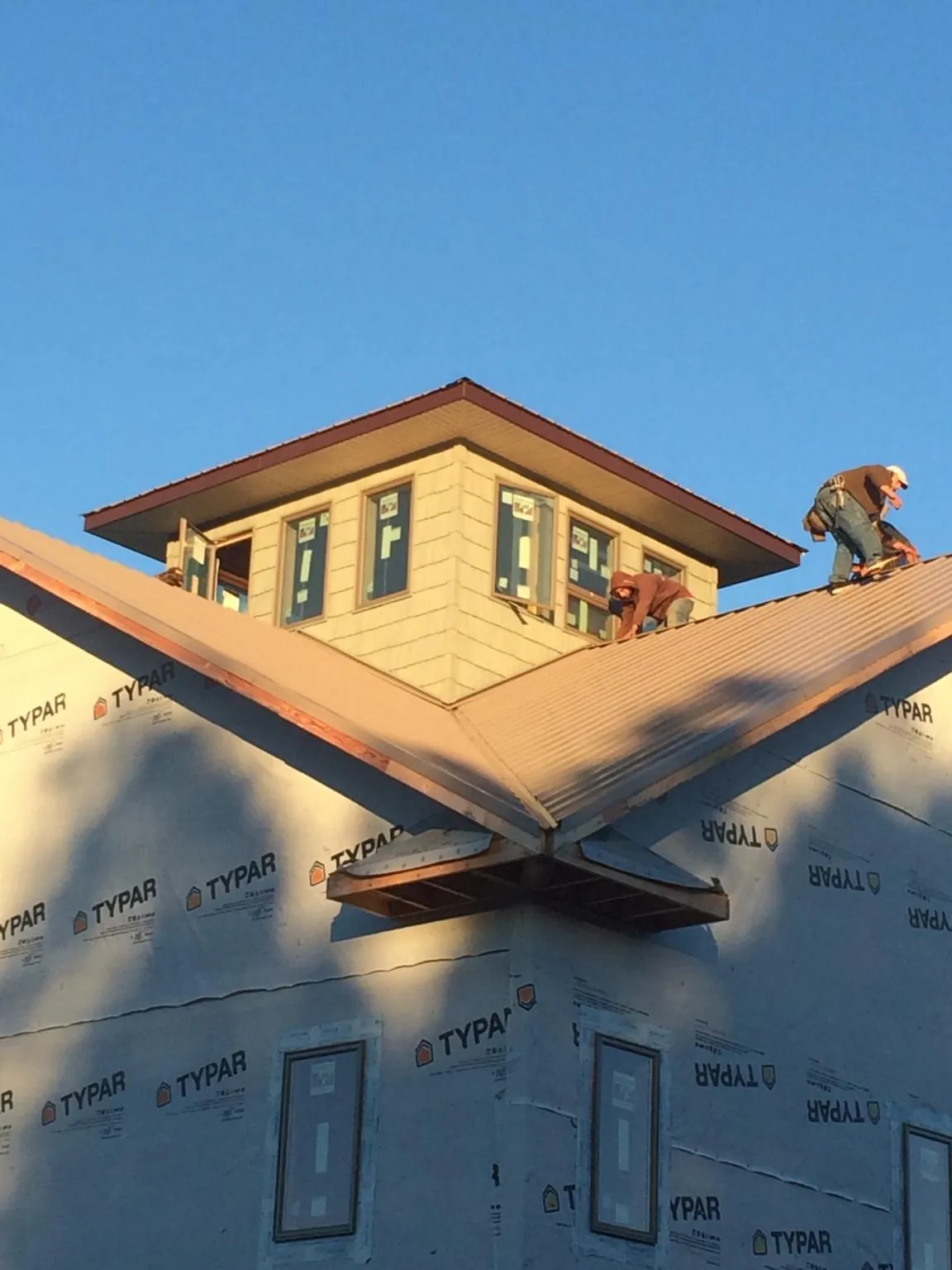 Roofers working around a rooftop cupola on a new metal roof at sunset — Roof Waterproofing in Fred by Roofing Brothers